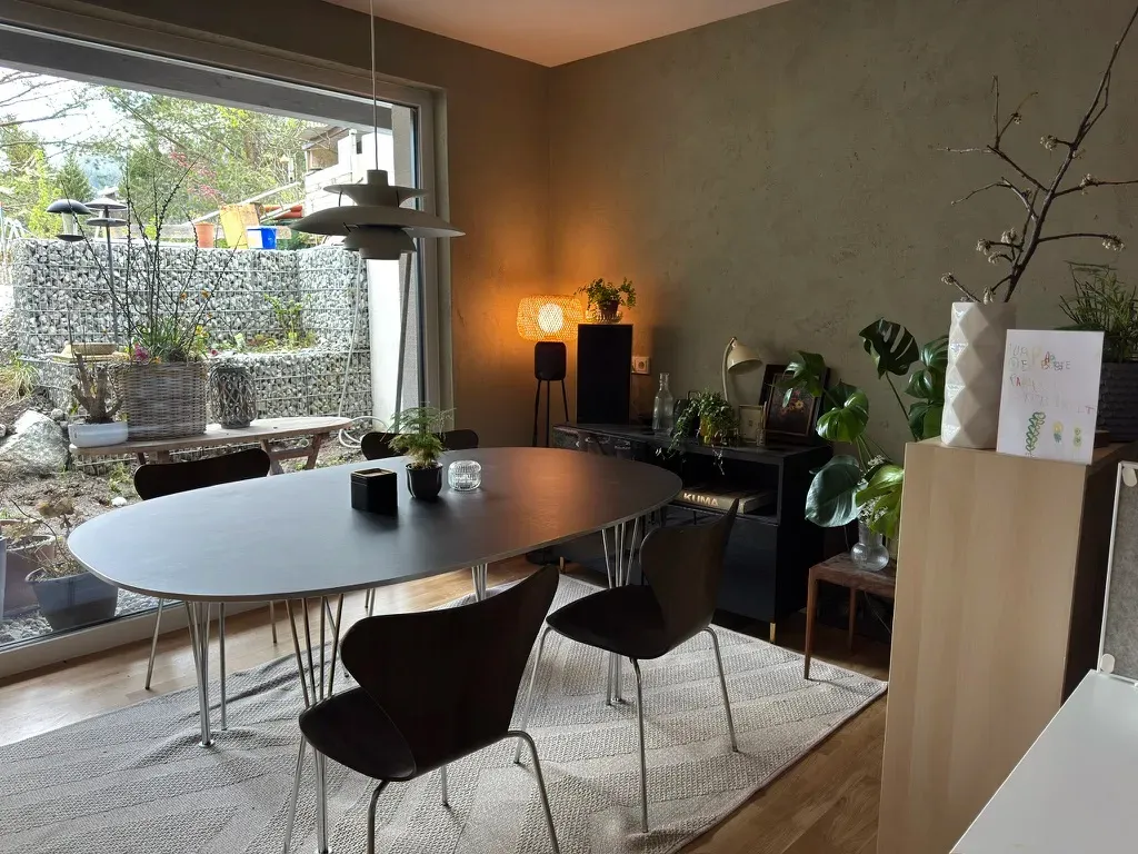 Büro im Untergeschoss, Tisch Superellipse und Stühle Serie 7 in Teak, darüber eine PH5-Leuchte, draußen der Kellergarten