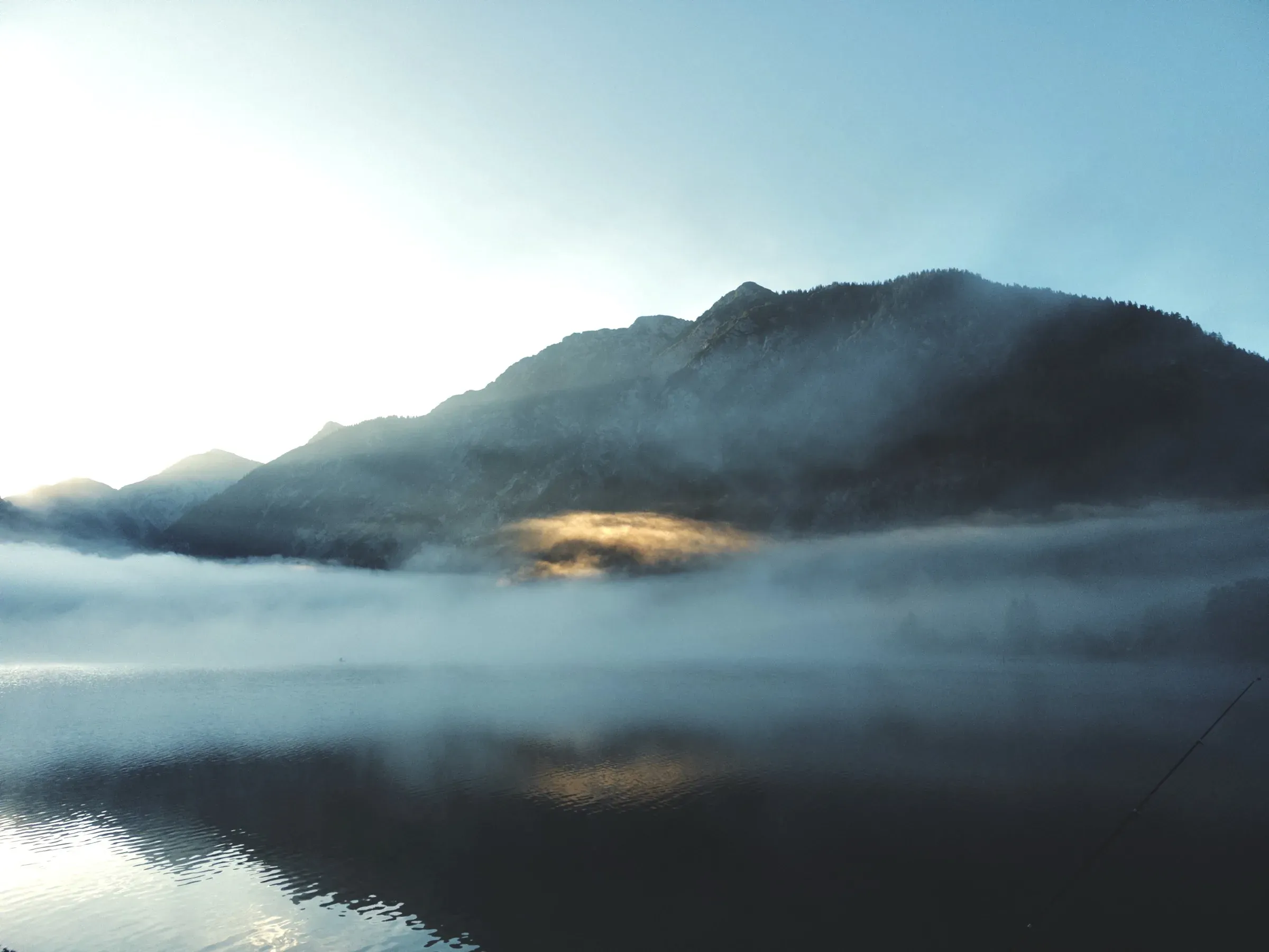 Der Heiterwanger See im Nebel, der Berg am anderen Ufer spiegelt sich im Wasser